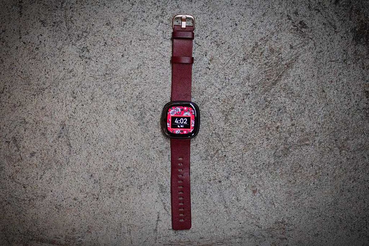 Fitbit Sense 2 with red-brown leather strap on concrete